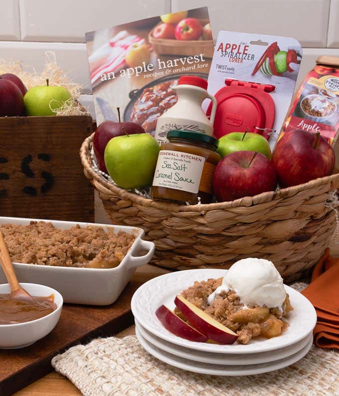 Gift basket with red and green apples, apple spiralizer & corer, An Apple Harvest: Recipes & Orchard Lore, apple crisp mix, a jug of apple cider concentrate, and a jar of sea salt caramel sauce